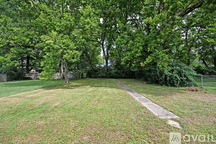 A grassy area with a dirt path and trees in the background.