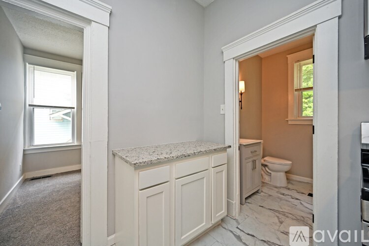 A bathroom with a toilet, sink, and cabinets.