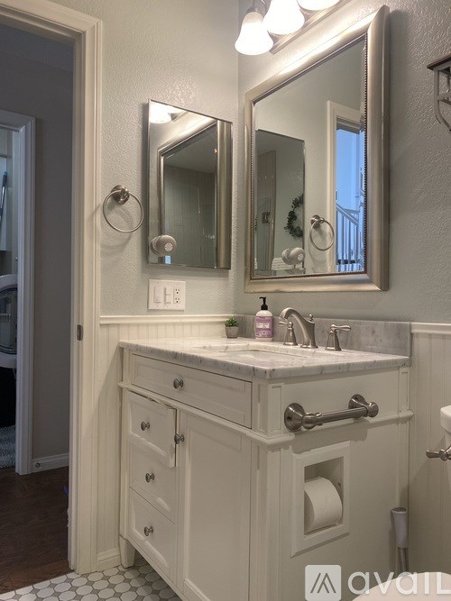 A bathroom with a white vanity and a large mirror.