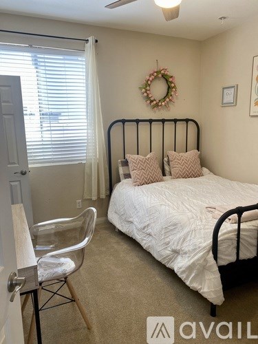A bedroom with a bed, chair, and a wreath on the wall.