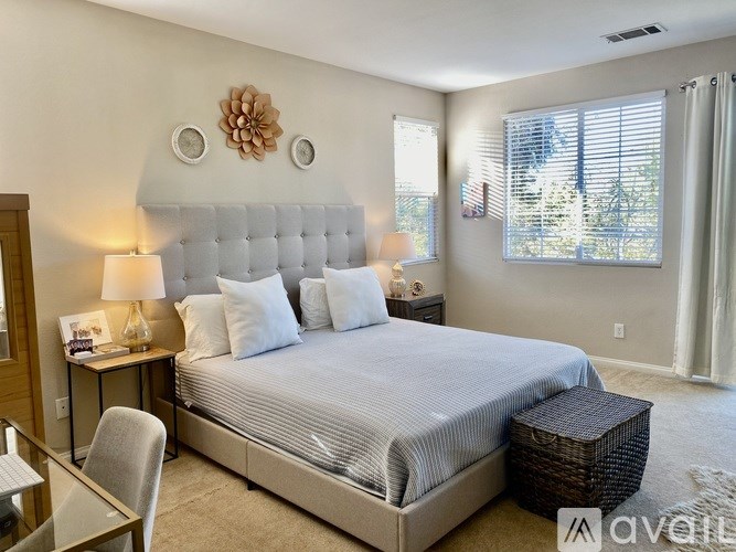 A bedroom with a large bed, a chair, and a table with a lamp on it.