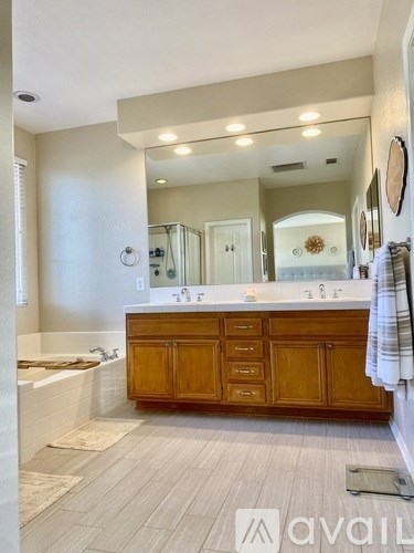 A bathroom with a wooden vanity and a large mirror.