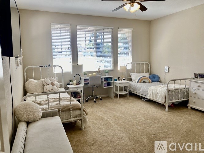 A room with two beds, a desk, and a chair.