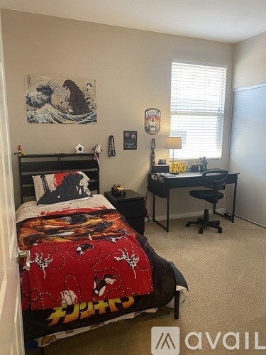 A bedroom with a bed, desk, and chair.