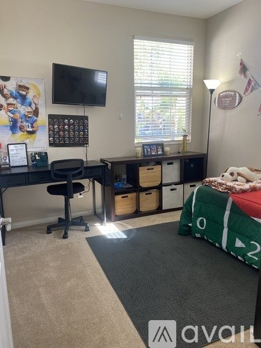 A room with a desk, chair, and a bed with a green and white comforter.