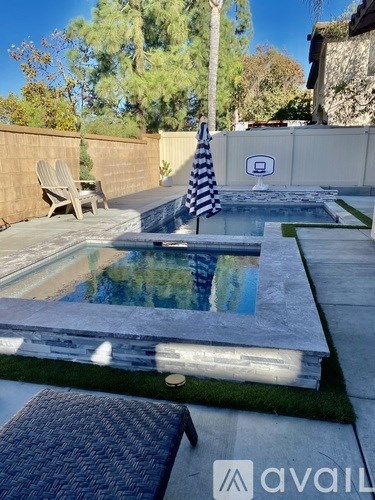 A pool with a striped umbrella and a chair.