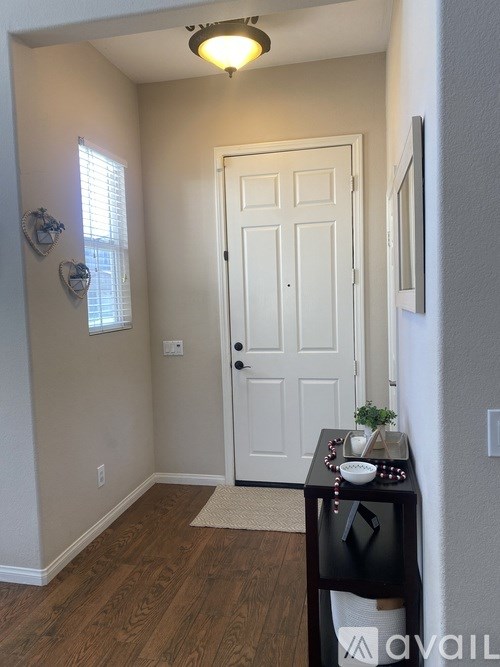 A hallway with a white door and a table with a plant on it.