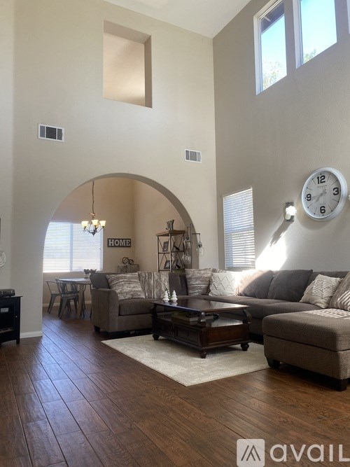 A living room with a couch, coffee table, and a clock on the wall.