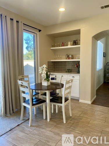 A dining room with a table set for two and a view of the backyard.