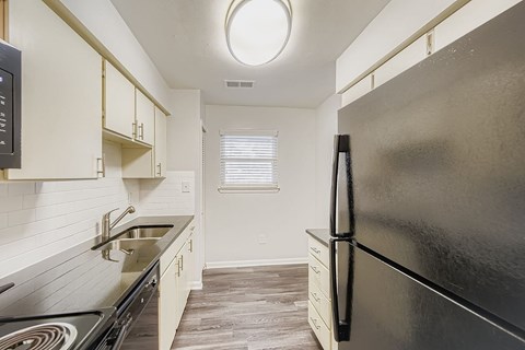 A modern kitchen with a black stove top oven and white cabinets.
