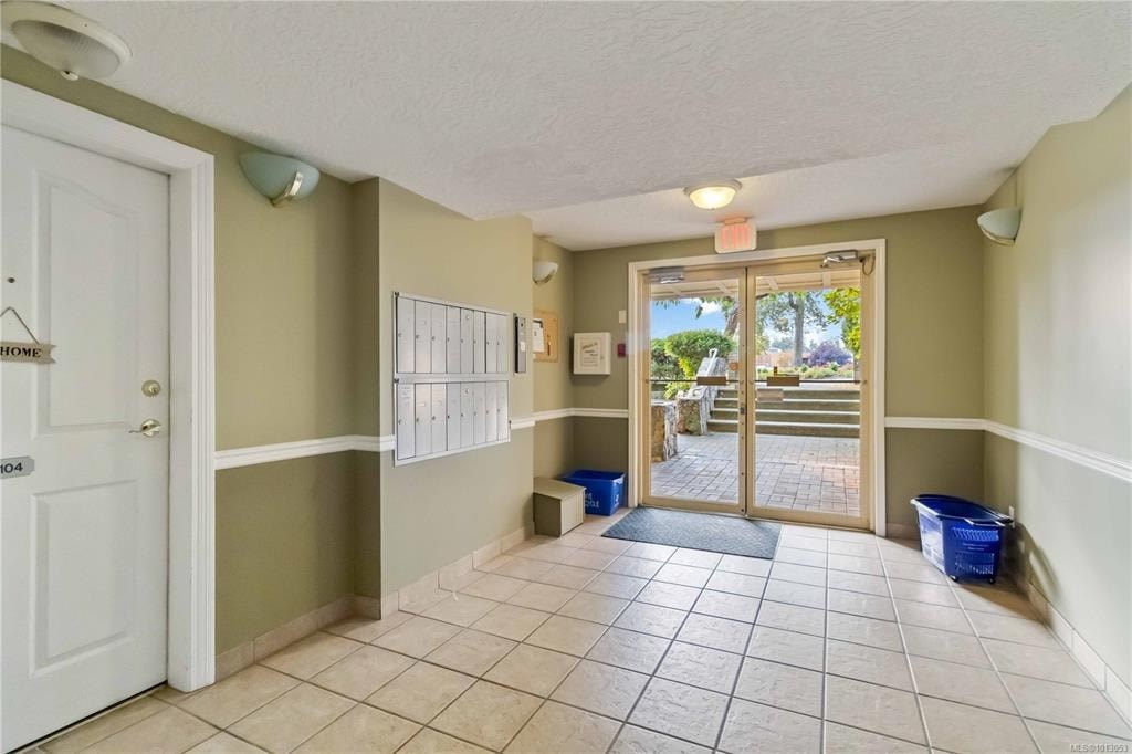 A room with a white door and a window with a view of trees and a house.