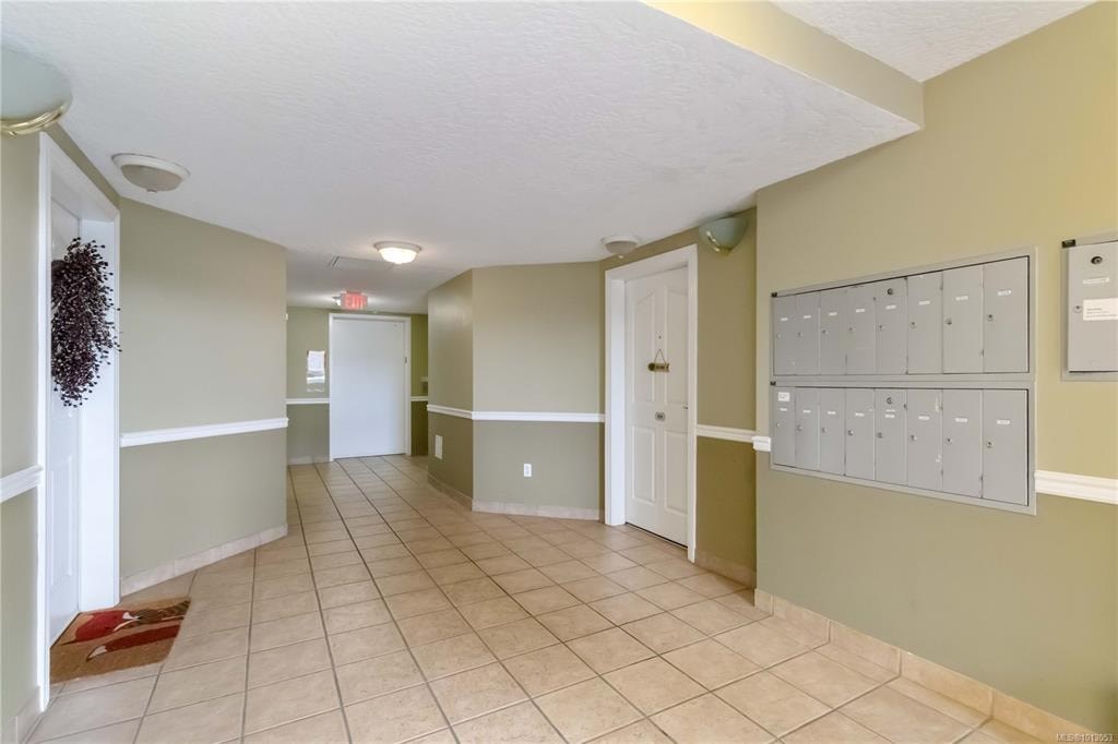 A hallway with a red rug on the floor and a mailbox on the wall.