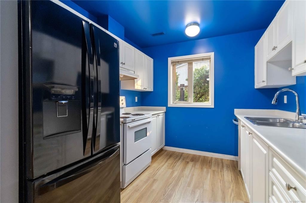 A kitchen with a black fridge and white cabinets.