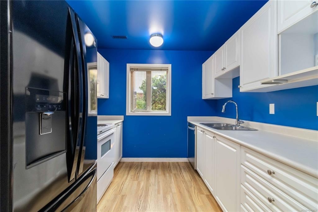 A kitchen with blue walls and white cabinets.