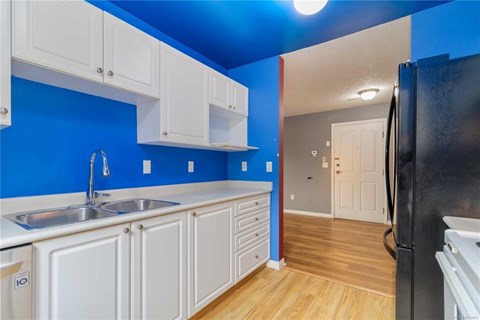A kitchen with white cabinets and a black refrigerator.