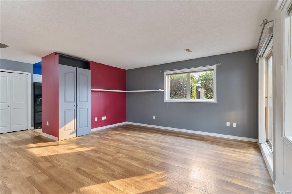 A room with wooden flooring and a red accent wall.