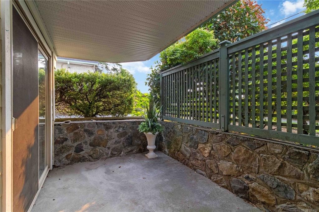 A patio with a green railing and a stone wall.