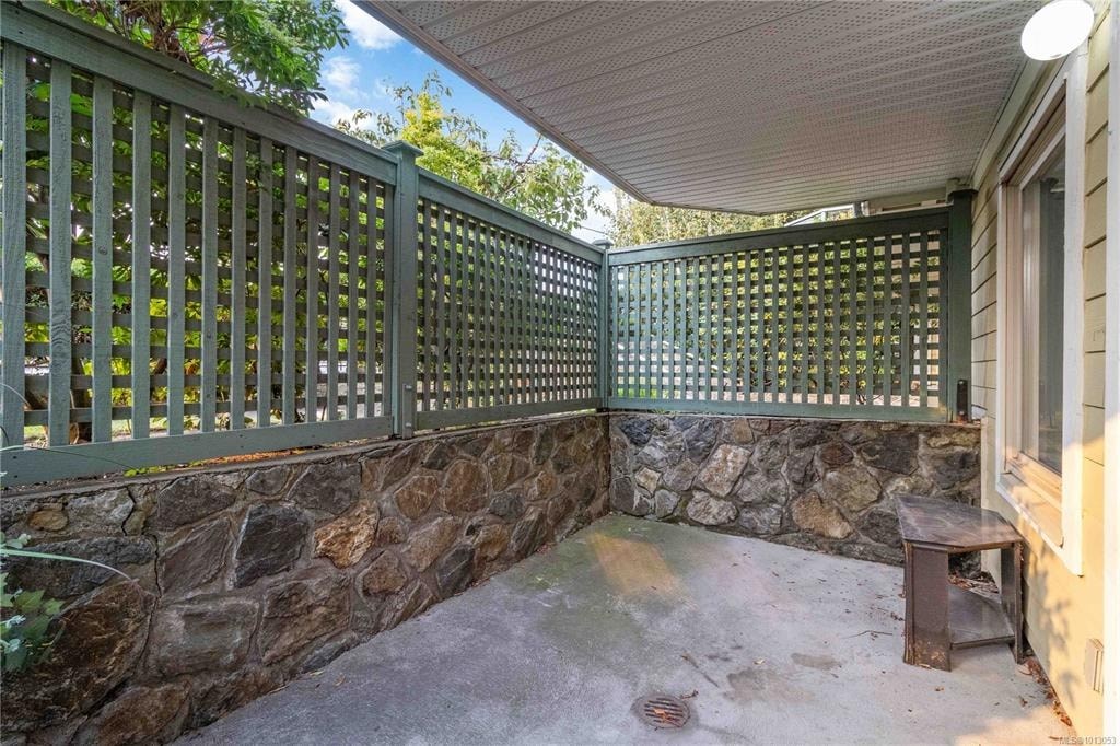 A patio with a green railing and a stone wall.
