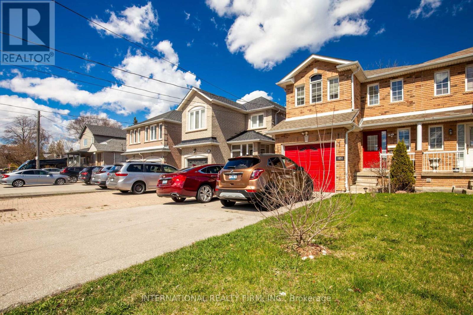 A row of houses with cars parked in front.