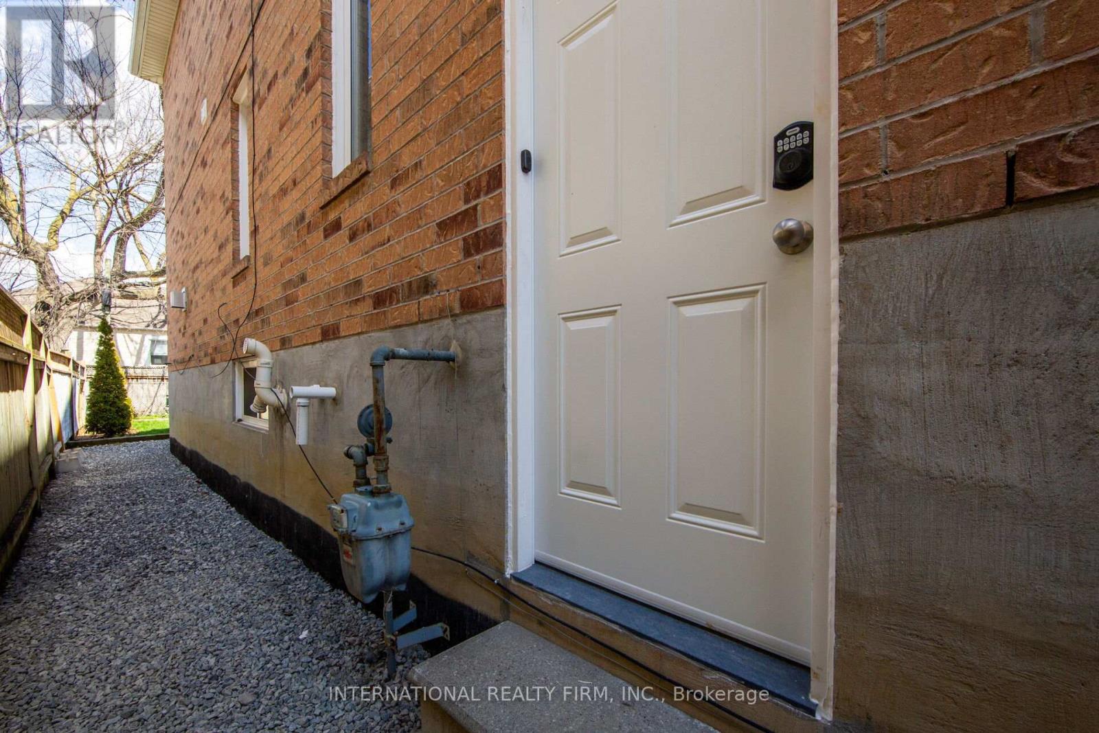 A white door is on the right side of a brick building.