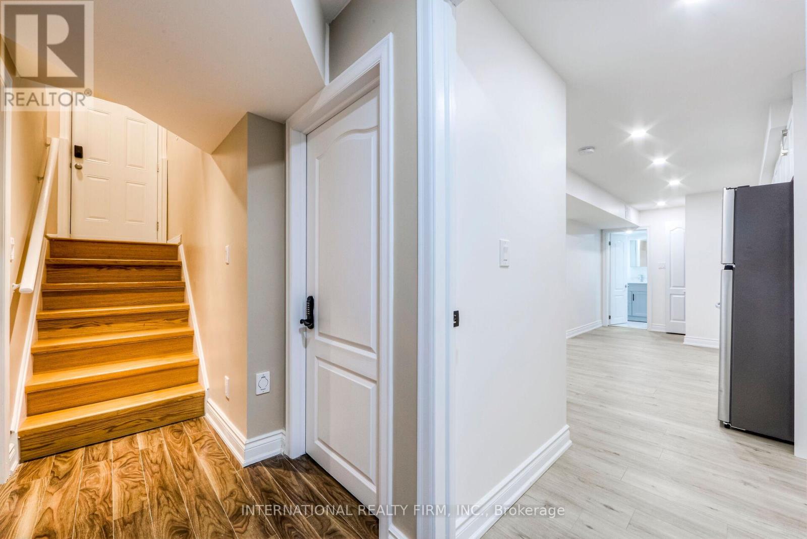 A hallway with a wooden staircase and a white door.