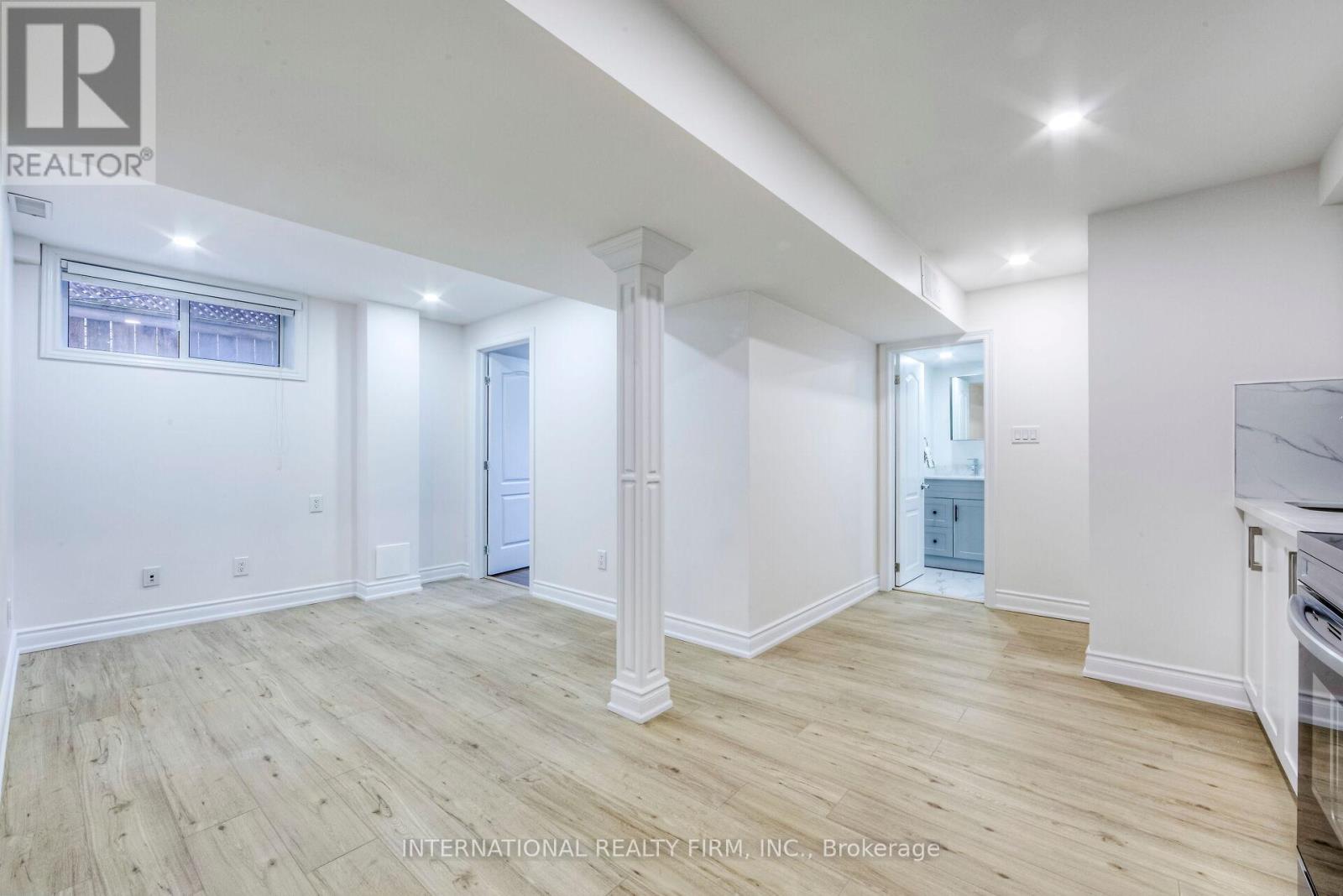 A spacious room with wooden flooring and white walls.