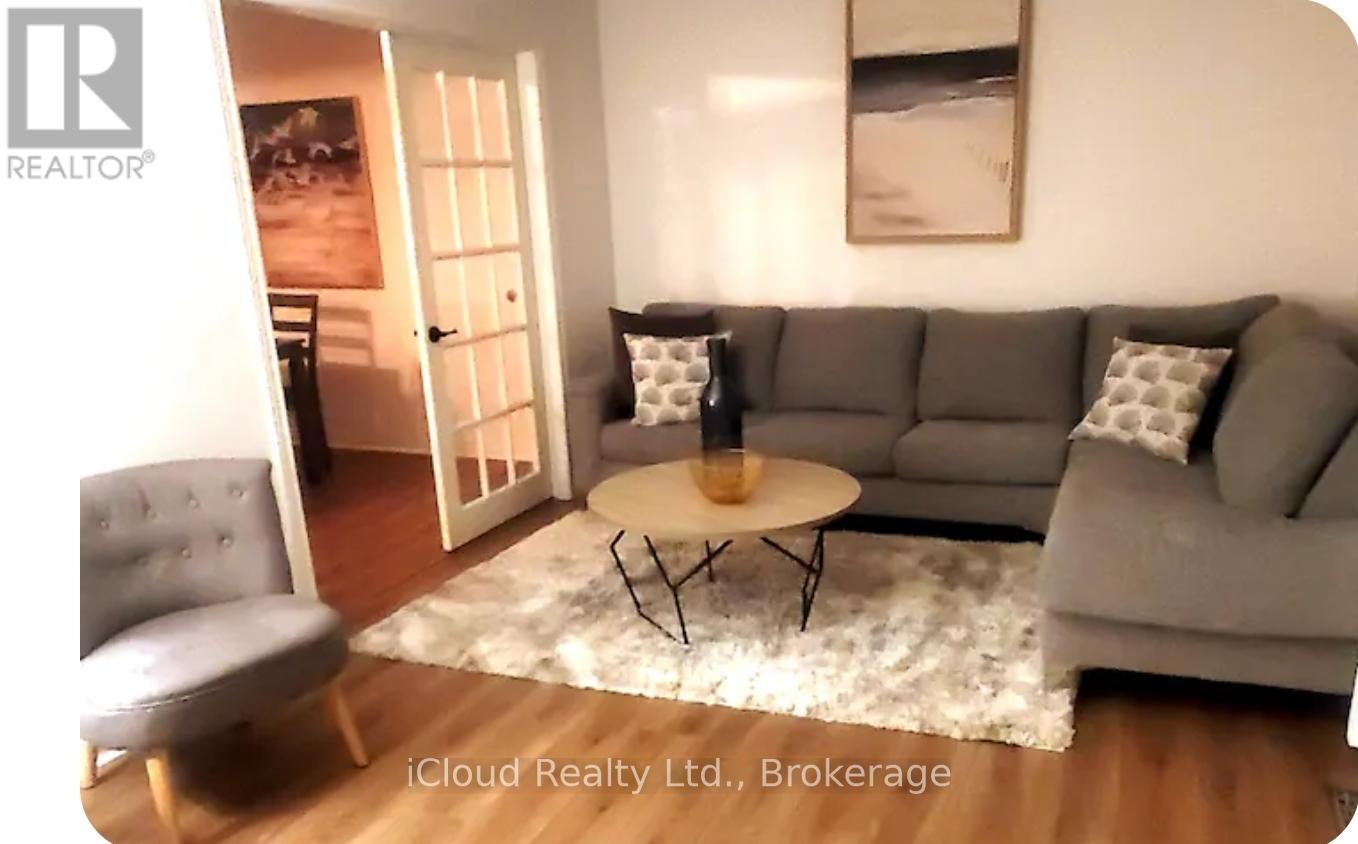 A living room with a grey couch, a round table, and a chair.