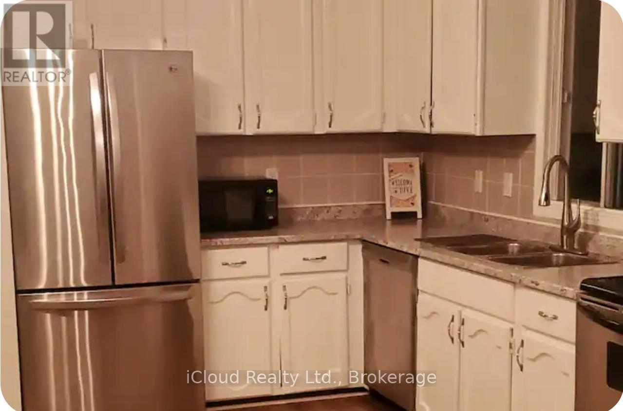 A kitchen with white cabinets and a stainless steel refrigerator.