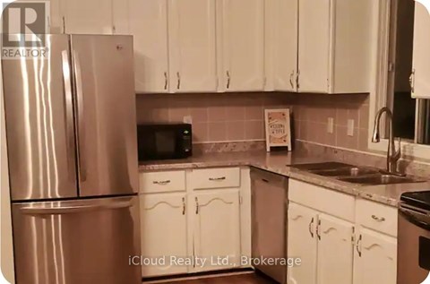 A kitchen with white cabinets and a stainless steel refrigerator.