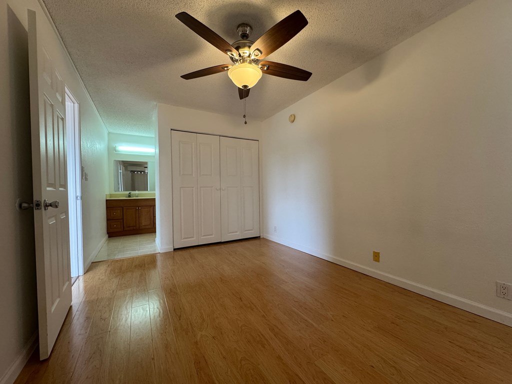 A room with a ceiling fan and wooden floors.