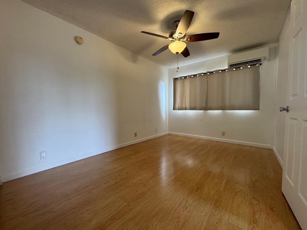 A room with a ceiling fan and wooden flooring.