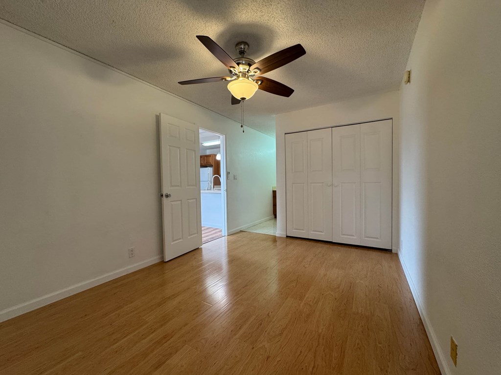 A room with a ceiling fan and wooden flooring.