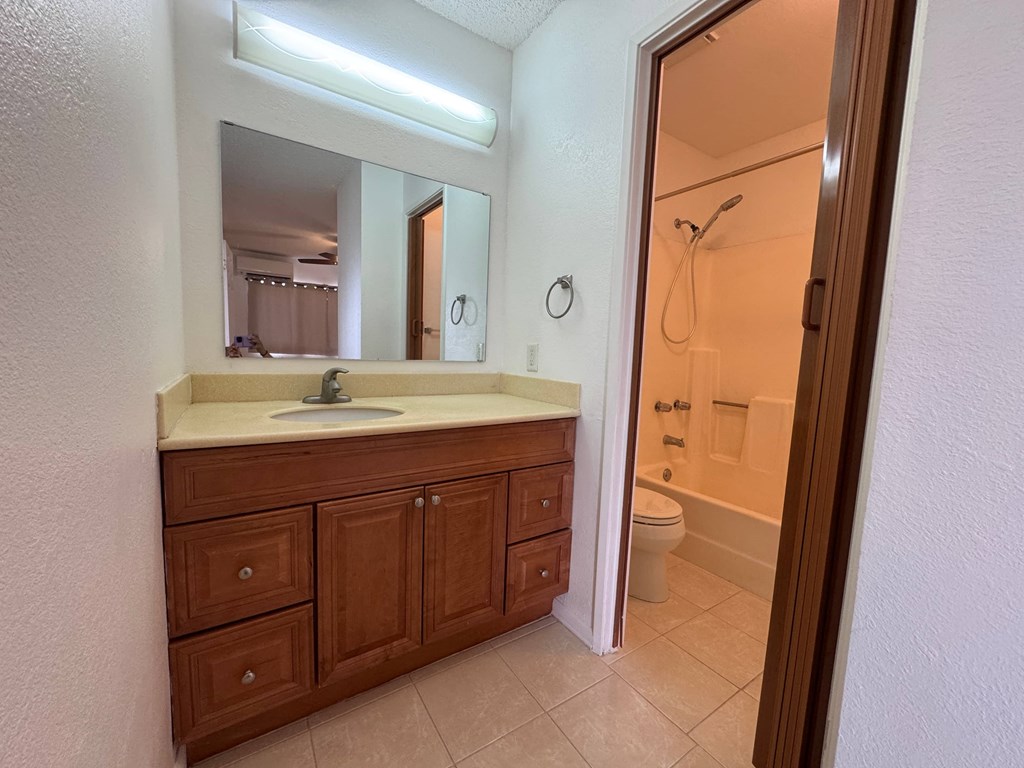 A bathroom with a sink, mirror, and wooden cabinets.