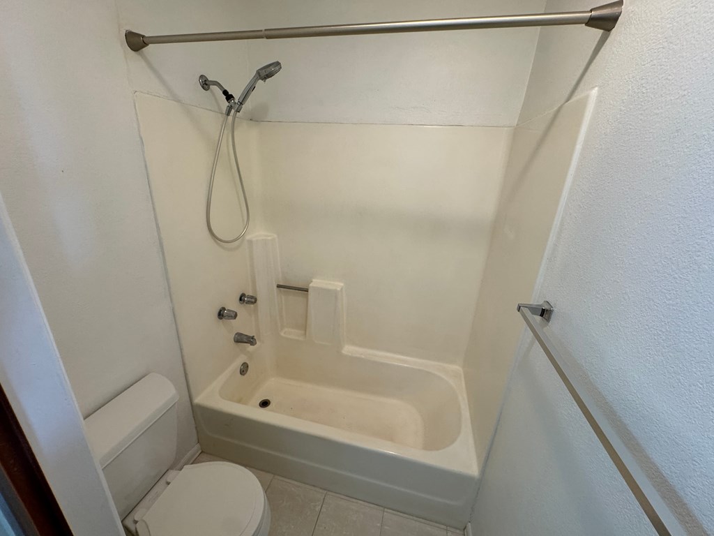 A white bathroom with a toilet, tub, and shower.