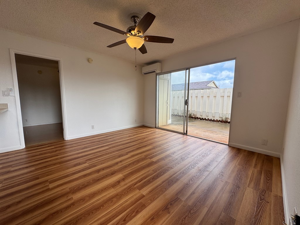 A room with a ceiling fan and sliding glass doors.