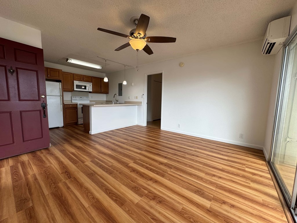 A room with a ceiling fan and wooden flooring.
