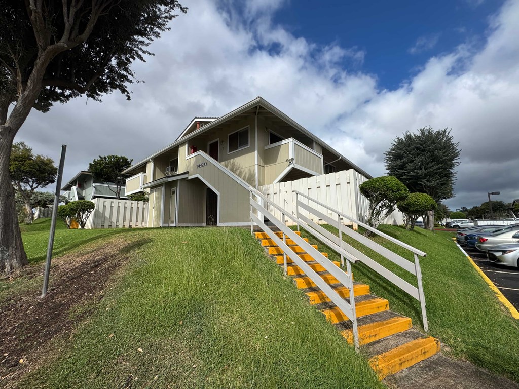 A modern house with a white fence and stairs leading to the front door.