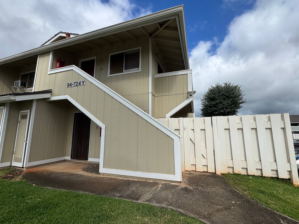 A two-story house with a beige exterior and a white picket fence.