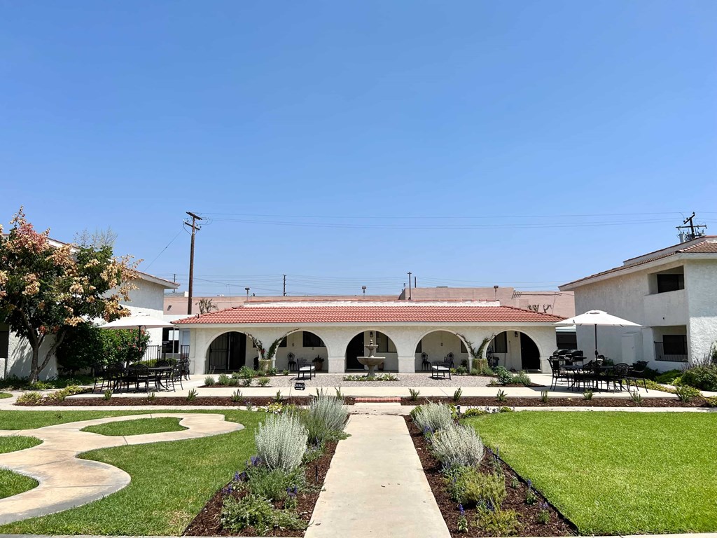 A white building with a red roof and a green lawn in front.
