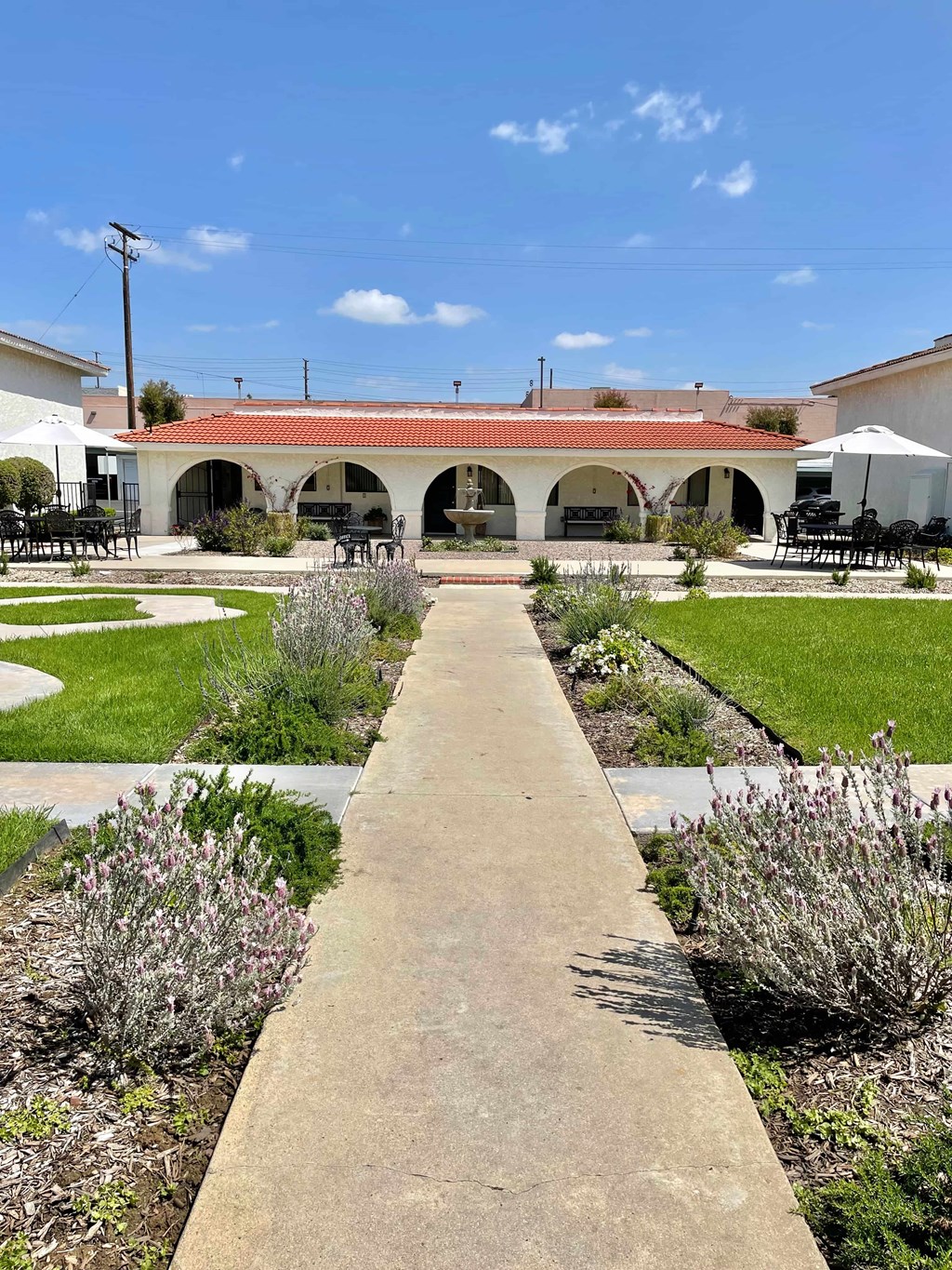 A long concrete walkway leads to a building with a red roof.