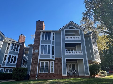 A grey and red brick house with a balcony.