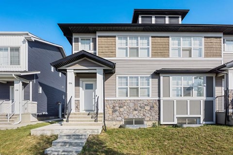 A modern house with a grey front and a stone wall.