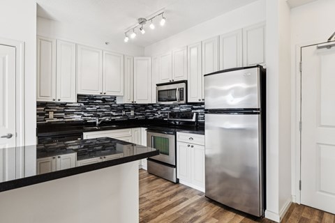 A modern kitchen with white cabinets and stainless steel appliances.