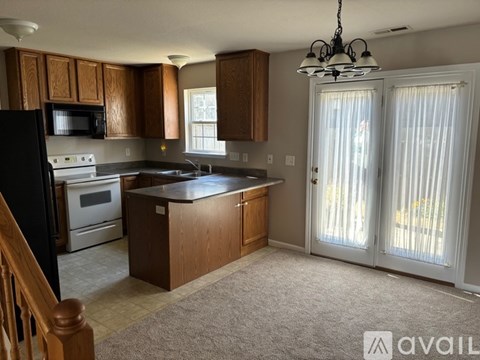 A kitchen with wooden cabinets and a black refrigerator.
