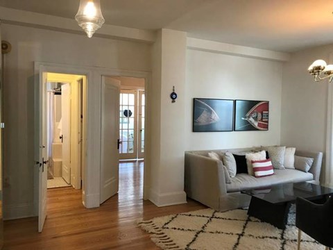 A living room with a grey couch and a painting on the wall.