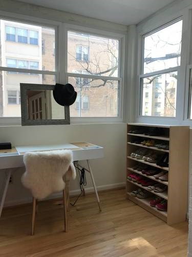 A room with a desk, chair, and shoe rack.