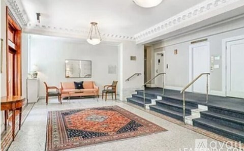A living room with a rug, a sofa, a table, and a staircase.