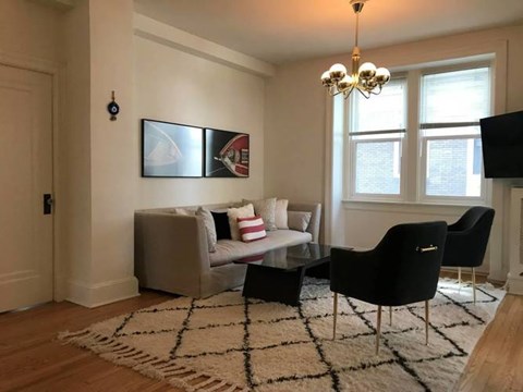 A living room with a grey couch, a black chair, and a chandelier.
