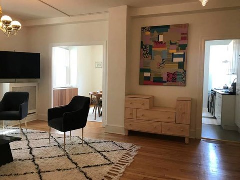 A living room with a black chair and a painting on the wall.