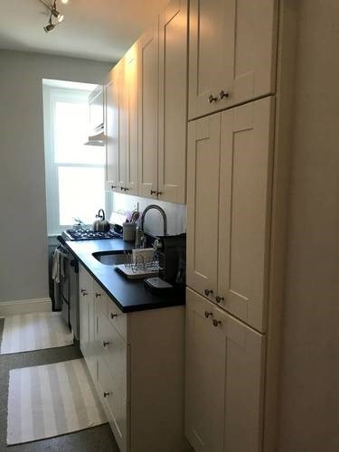 A kitchen with white cabinets and a black countertop.